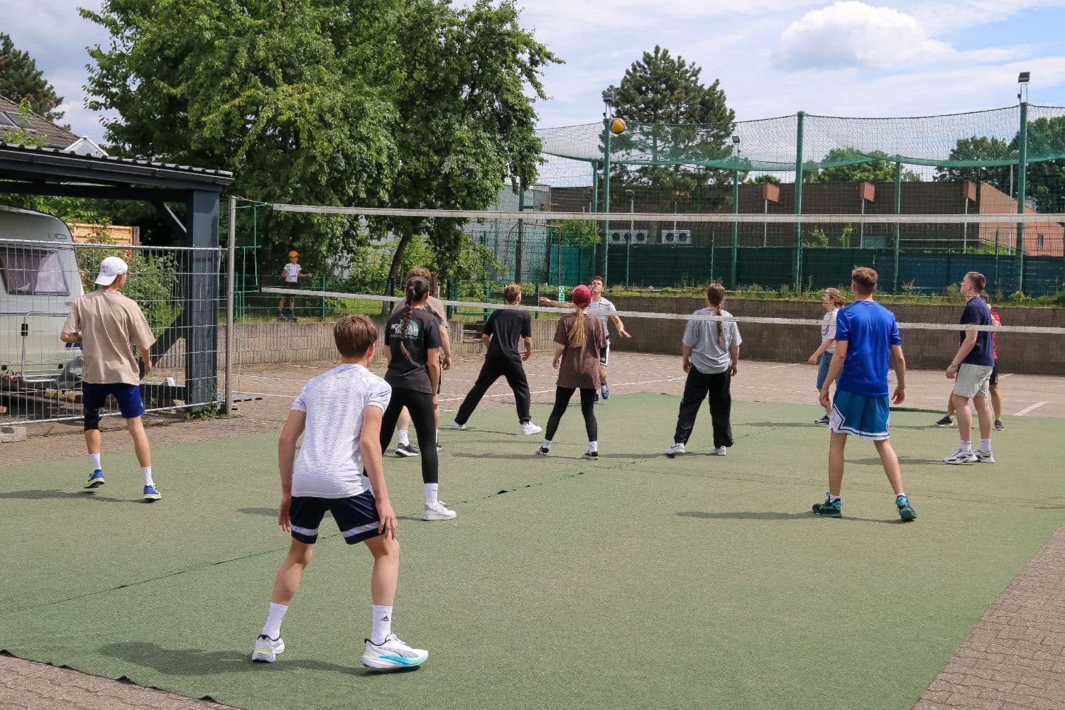Jugendliche spielen draußen auf dem Gemeindegelände Volleyball